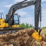 Una Excavadora 200G recoge tierra y césped en un lugar de trabajo.